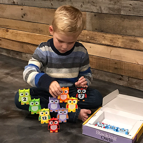 Young boy playing with Stacking Owls Montessori wooden toy by Discovery Toys