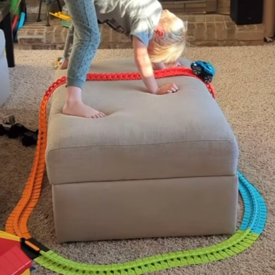 Boy playing with Crazy Climb Track by Discovery Toys over the ottoman